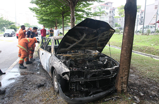 Firefighters inspecting the burnt car in Taman Kinrara