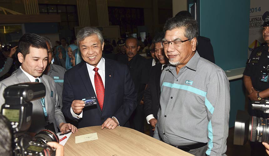 Ahmad Zahid (kiri) menunjukkan kad debit BSN baharunya sambil disaksikan oleh Pengerusi BSN Tan Sri Abu Bakar Abdullah. - Gambar BSN