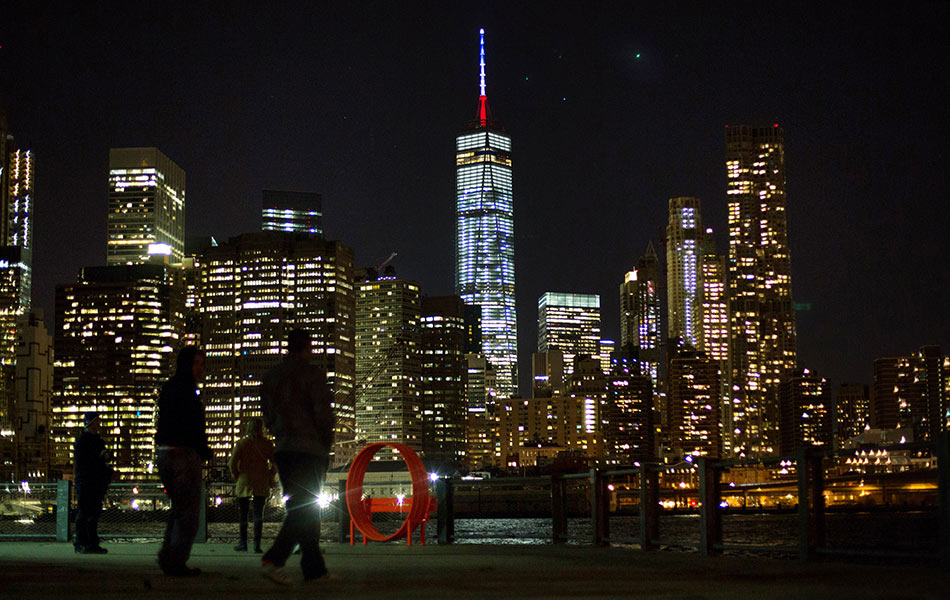 Pusat Dagangan Dunia di New York turut disinari warna merah, biru dan putih, warna-warna bendera Perancis bagi memperingati mangsa serangan bersiri di Paris yang meragut lebih 100 nyawa pada Jumaat. - AP Photo/Kevin Hagen