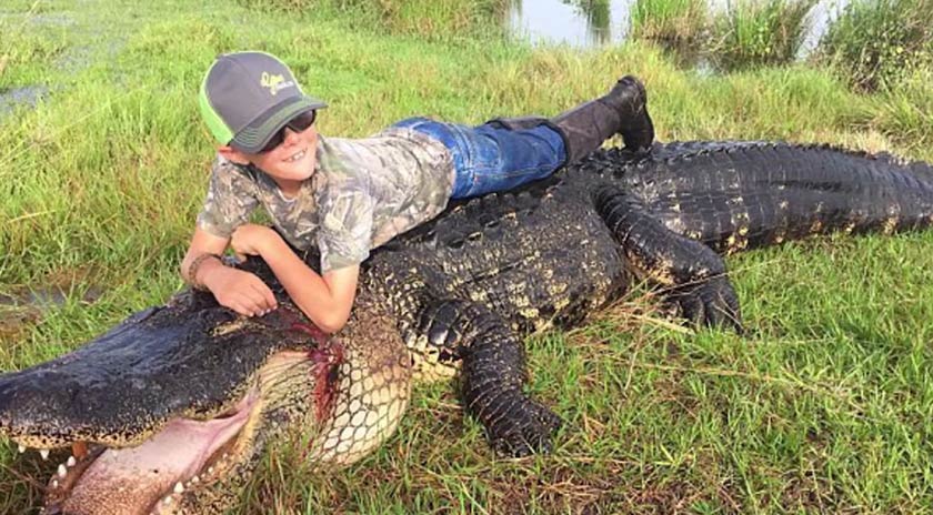 Seorang kanak-kanak lelaki bergambar dengan bangkai buaya yang telah menggemparkan orang ramai itu. - Foto sumber YouTube