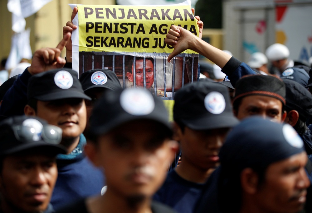 A protester holds a banner outside a court during the first day of the blasphemy trial of Jakarta's Governor Basuki Tjahaja Purnama, also known as Ahok, in Jakarta, Indonesia December 13, 2016. The banner reads 