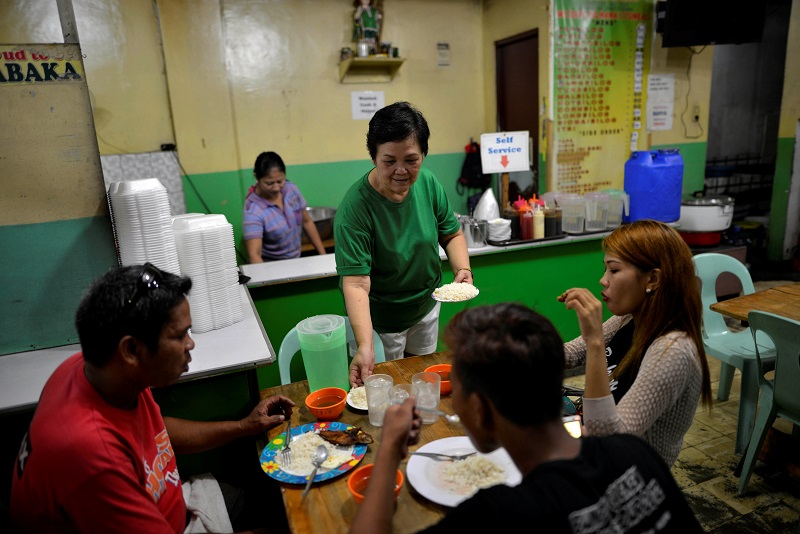 Felicidad Magdayao, 59, owner of a fast-food restaurant serves customers in Manila, Philippines September 27, 2016. 
