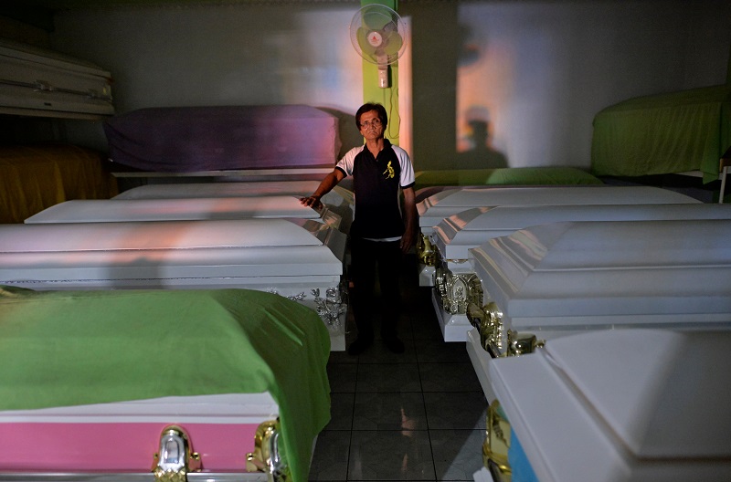 Orly Fernandez, 64, operational manager at Eusebio Funeral Services poses for a photograph next to empty coffins in Navotas city, Metro Manila, Philippines October 30, 2016. Fernandez lives in the funeral parlour. 