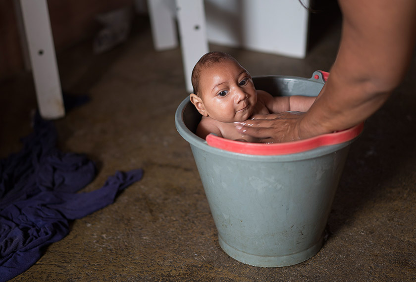 In this Dec. 23, 2015 photo, Solange Ferreira bathes her son Jose Wesley in a bucket at their house in Poco Fundo, Pernambuco state, Brazil. Ferreira says her son enjoys being in the water, she places him in the bucket several times a day to calm him. (AP Photo/Felipe Dana)