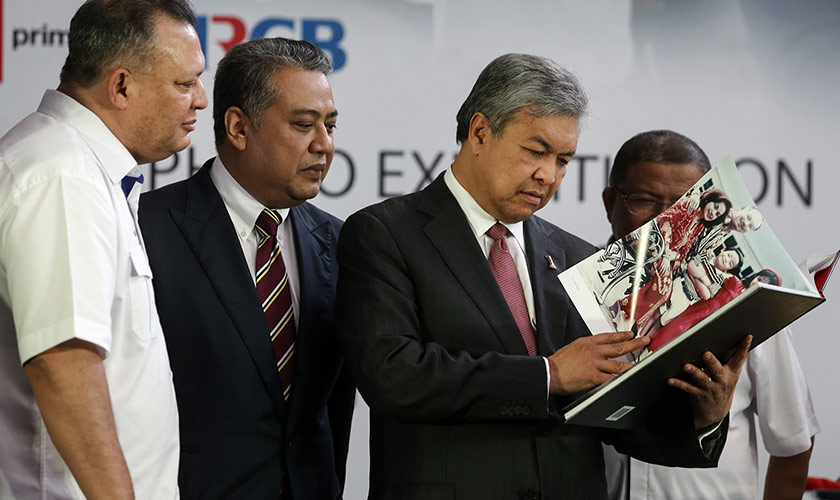 Ahmad Zahid browsing through the book 'Najib Razak 40 Years 40 Pictures' at KL Sentral earlier today. - Astro AWANI/Shahir Omar