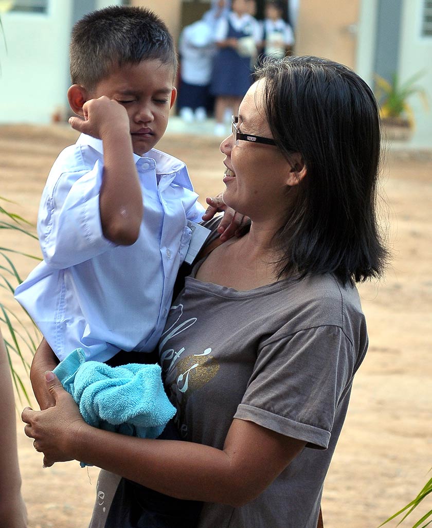 Pelajar tahun satu, Khun Krissadorn a/l Pricha yang demam terpaksa didukung ibunya Chee Siew Chean, 36, ketika tinjauan sesi persekolahan baru 2016 di Sekolah Jenis Kebangsaan Cina (SJKC) Kou Hua, Ahad. - Foto Bernama