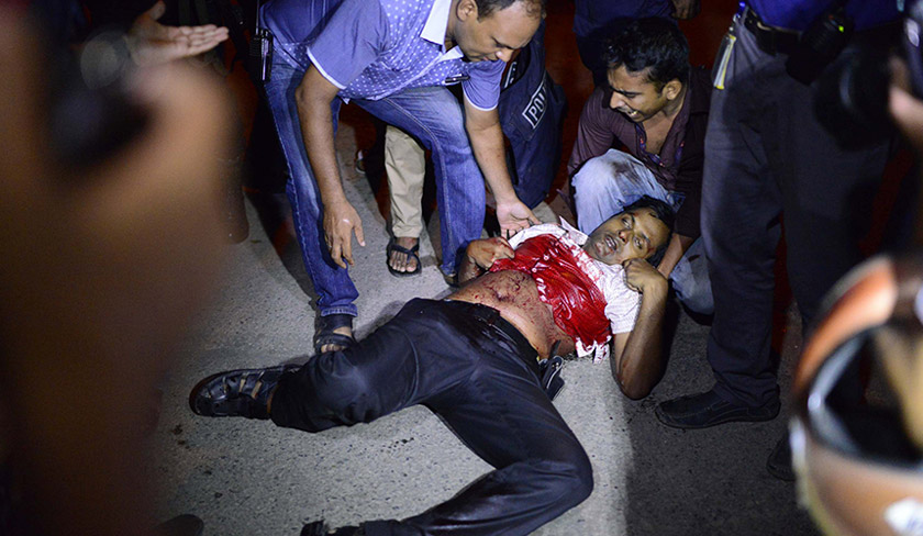 Orang ramai membantu seorang lelaki yang cedera dalam insiden tembakan di Dhaka. - Foto AP