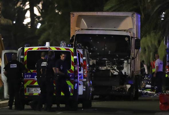 Police officers and rescued workers stand near a truck that ploughed into a crowd leaving a fireworks display in the French Riviera town of Nice on July 14, 2016. - AFP Photo