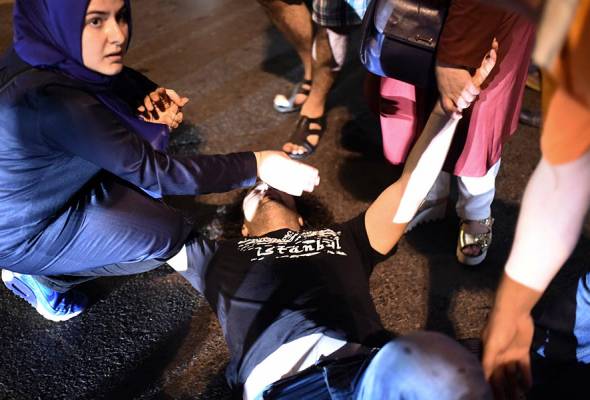 Seorang wanita membantu seorang lelaki yang ditembak selepas pertempuran dengan tentera Turki di pintu masuk ke jambatan Bosphorus di Istanbul pada 16 Julai 2016. - Foto AFP