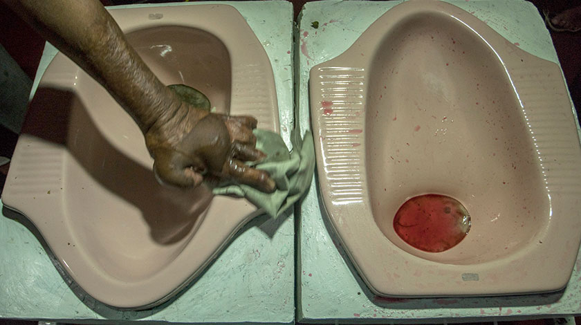 A worker cleaning up a squat toilet display from where customers ate a meal at the
