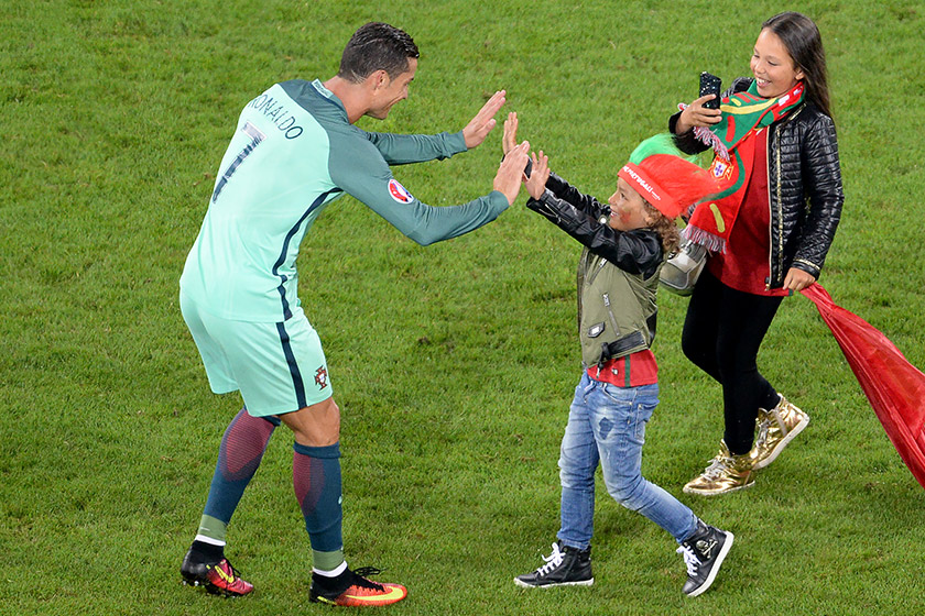 Bintang pasukan Portugal Cristiano Ronaldo meraikan kejayaan pasukannya mara ke suku akhir dengan seorang peminat cilik. - AFP PHOTO / FRANCOIS LO PRESTI