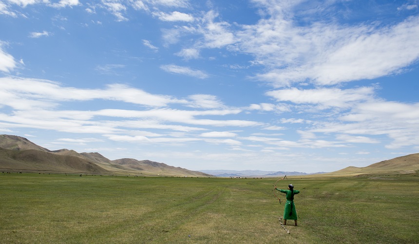 In this Sunday, June 5, 2016, file photo, a mongolian archer shoots a bow and arrow as U.S. Secretary of State John Kerry attends a Naadam ceremony, a competition which traditionally includes horse racing, Mongolian wrestling and archery, in Ulaanbaatar, Mongolia. Mongolians vote in parliamentary elections Wednesday, June 29, 2016, with sentiment weighed by a sharp downturn in the landlocked Asian nation’s crucial mining sector, rising unemployment and political disillusionment. Mongolia’s mining- and animal herding-dependent economy has been dragged down by weak domestic demand and a sharp decline in exports, impoverishing thousands of former herders who had moved to its few cities looking for jobs. (Saul Loeb/Pool Photo via AP, File)