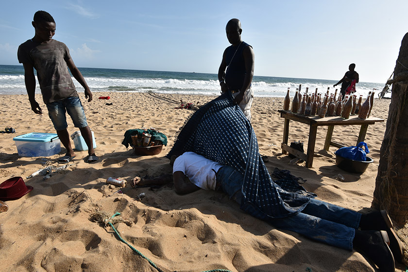 People put a blanket on a body lying on the beach after gunmen went on a shooting rampage in the Ivory Coast resort of Grand-Bassam on March 13. - AFP Photo/Sia-Kambou