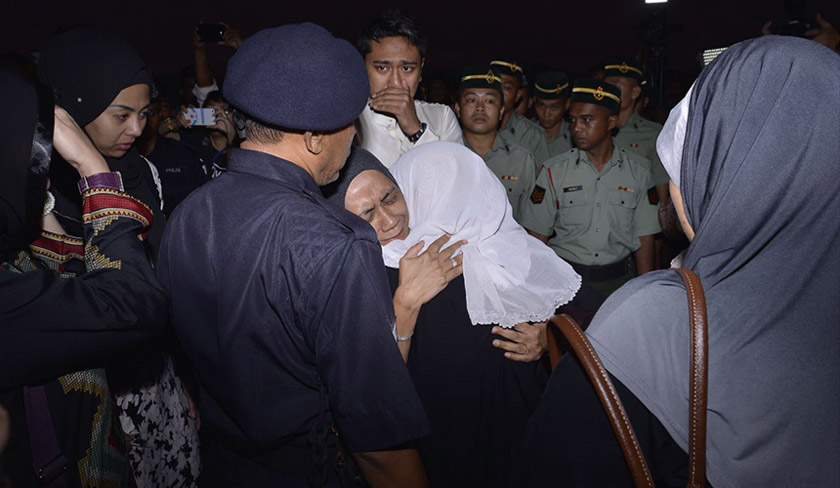 Loved ones of Wan Mohammad Khair-il Anuar embracing one another in sorrow.