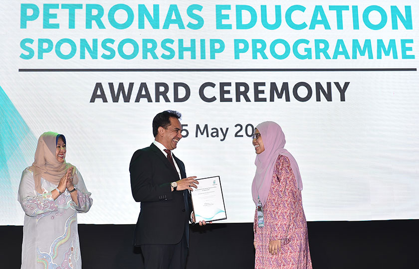 Wan Zulkiflee menyampaikan sijil tawaran biasiswa PETRONAS kepada salah seorang pelajar sambil diperhatikan Raiha. - Foto PETRONAS