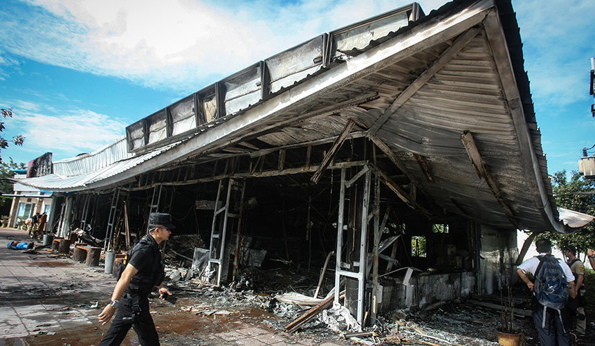 A police officer walks past a 7-11 convenience store in the Thai southern province of Pattani on Nov 3, 2016, after it was damaged in a bombing the night before. - AFP