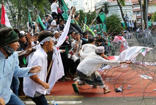 Muslim protesters pull razor wire blocking a road that leads to the presidential palace during a rally against Jakarta Governor Basuki Tjahaja Purnama in Jakarta, Indonesia, Friday, Nov. 4, 2016. -AP