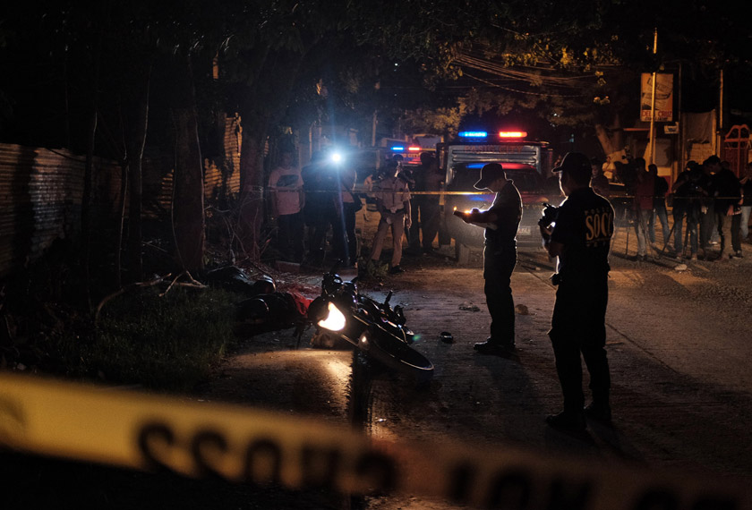Crime scene investigators examine the bodies of two uspected drug dealers that where shot dead by police in an alleged shootout in a suburban area in Pasig city on Sept. 23. Photo by Jes Aznar for The Washington Post