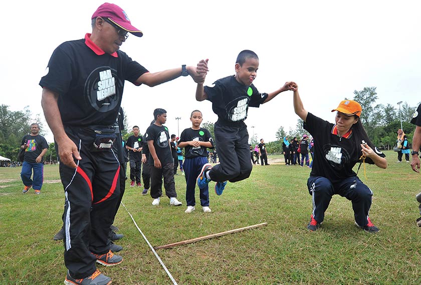 Pelajar cacat penglihatan dari Sekolah Kebangsaan Pendidikan Khas Kuala Terengganu Adid Muayyad Zamri, 12, dibantu oleh gurunya untuk melompat sewaktu menyertai acara Forward Squat Jump sempena Hari Sukan Negara di Batu Burok hari ini. - Foto Bernama