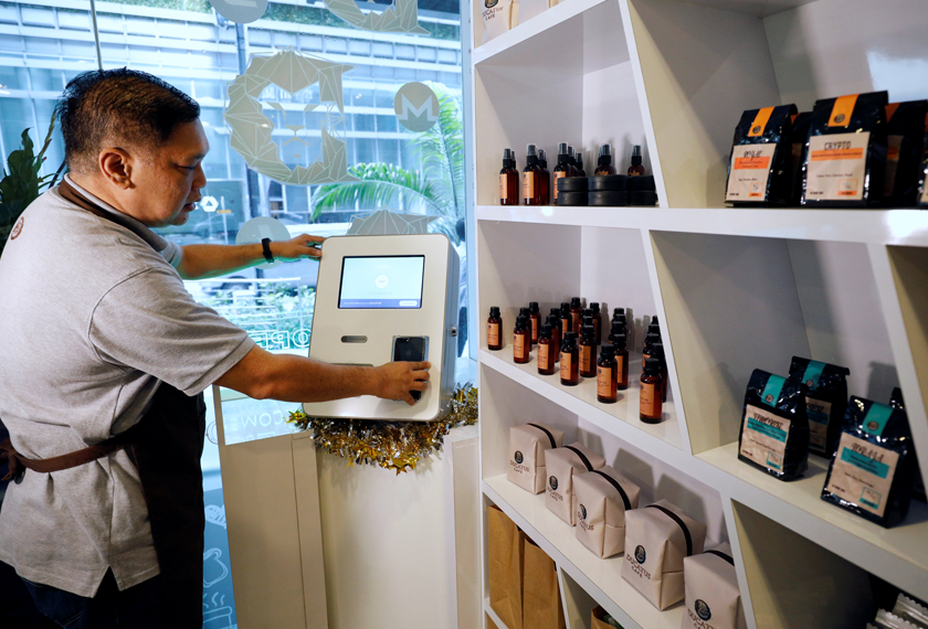 Ducatus franchise manager Philip Lim shows how a deposit is made at a Bitcoin ATM at the opening of their first cashless cafe that accepts cryptocurrencies such as Bitcoin on Dec 21, 2017. - REUTERS
