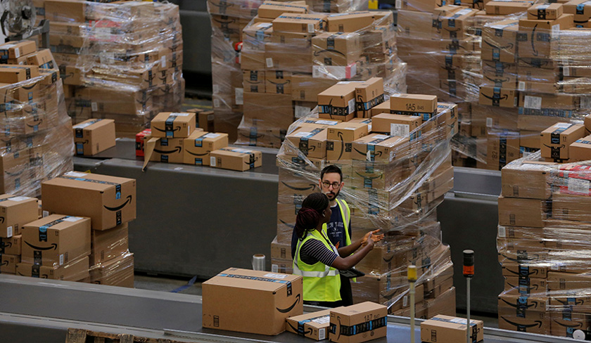 Workers walk past boxes to be shipped inside of an Amazon fulfillment center in Robbinsville, New Jersey, U.S. on Nov 27, 2017. - REUTERS