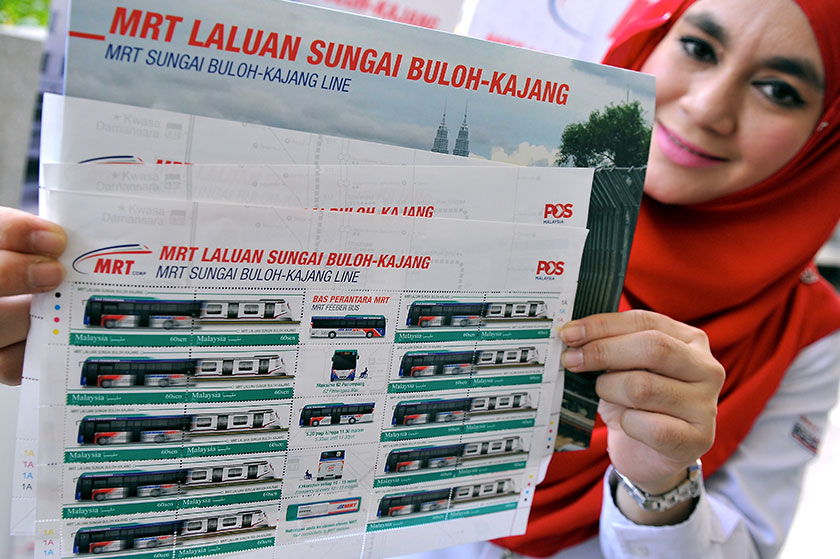 Petugas Pos Malaysia Faizah Mustapakamal menunjukkan setem Transit Aliran Massa (MRT), yang akan dikeluarkan sempena pelancaran MRT Isnin ini. - Foto Bernama