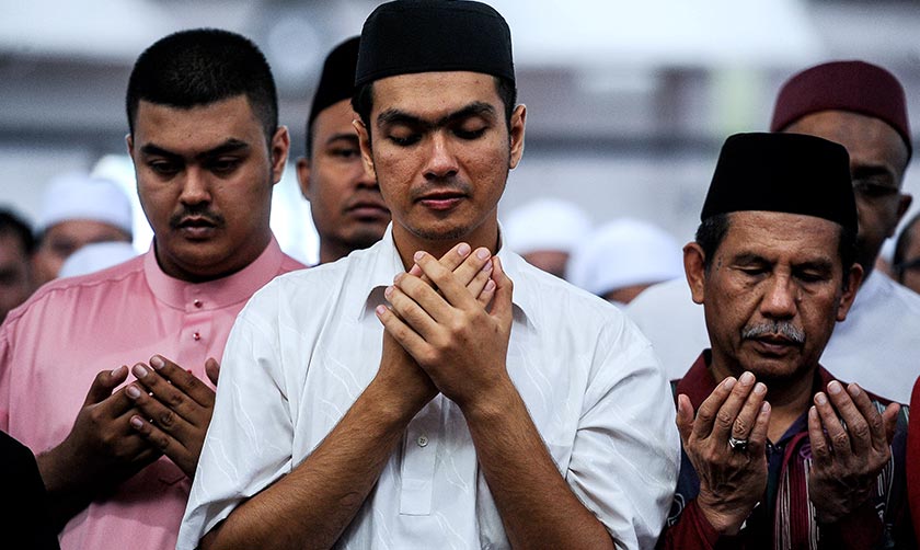 Anak Allahyarham Tan Sri Jins Shamsudin Putera Hang Nadim ketika mengaminkan doa selepas solat jenazah bapanya di Masjid Al-Ridhuan hari ini. - Foto Bernama
