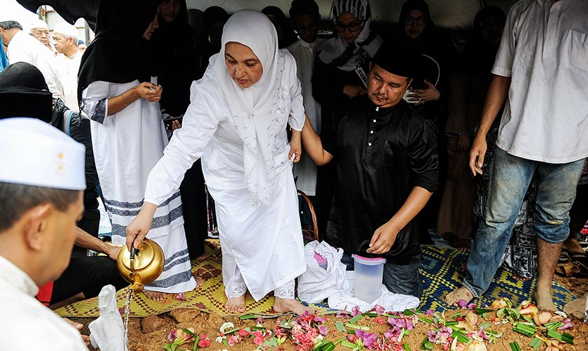 Balu Allahyarham Tan Sri Jins Shamsuddin Puan Sri Halijah Abdullah (tengah) menyiram air mawar ke atas pusara suaminya di Tanah Perkuburan Islam Ulu Kelang hari ini.- Foto Bernama