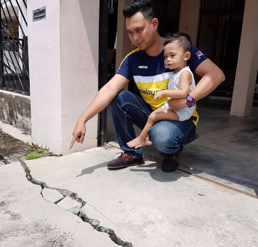 A resident showing the cracks that appeared at the entrance of his house in Taman Sri Raya. Pix Astro AWANI