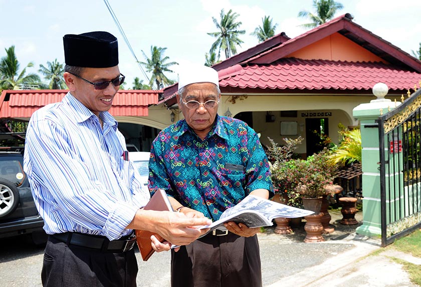 Hussin (kanan) berbual dengan jiran, Mohd Sabri Alias di hadapan rumahnya di Felda Lui Timur. - Bernama
