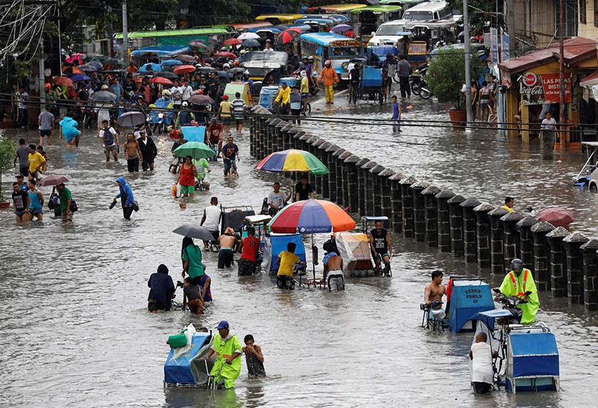 Residents wade and ride on pedicabs along a partially flooded road, in Las Pinas Metro Manila as a storm sweeps across the main Luzon island, Philippines on Sept 12, 2017. - REUTERS