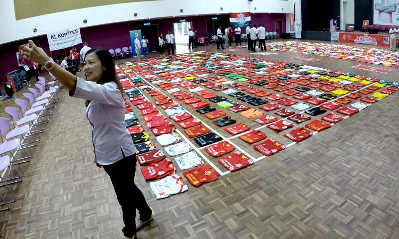 Salah seorang ahli KL Kopites berswafoto berlatarbelakangkan jersi-jersi Liverpool yang dikumpul penyokong-penyokong di Malaysia.