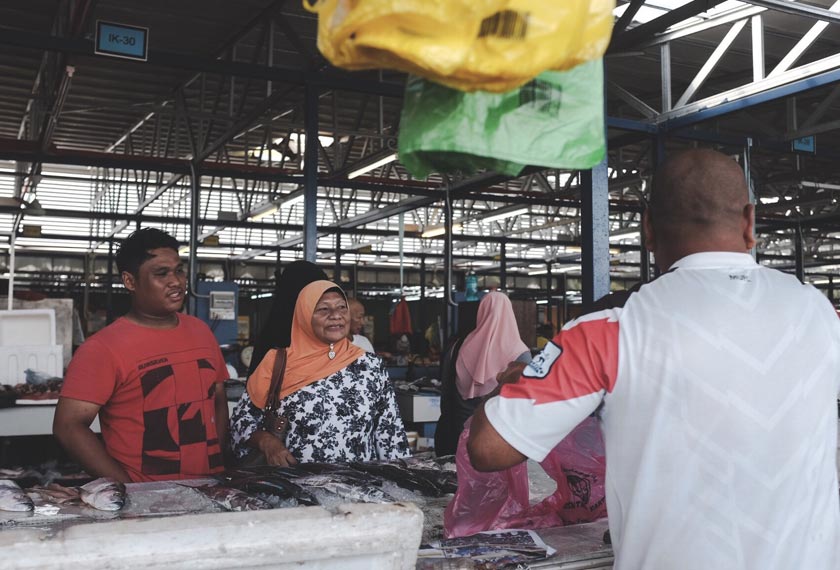 Jalal cuba menarik pelanggan untuk membeli barangan basah jualannya.