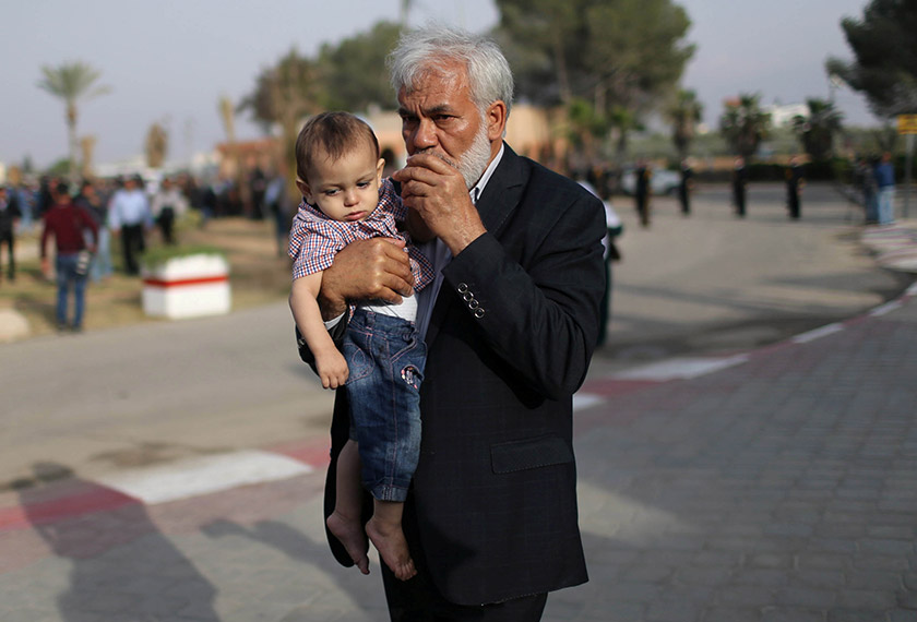 Anak lelaki Dr Fadi dipegang datuknya ketika jenazah Dr Fadi tiba di Semenanjung Gaza pada 26 April 2019. - REUTERS