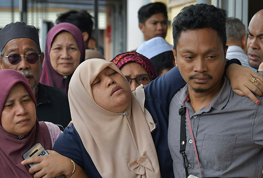 Nursyahida Abdullah yang hampir pengsan, dipapah suaminya, Zawawi Wahab, selepas ketiga-tiga jenazah anak mereka ditemui oleh pasukan penyelamat ketika ditemui di Hospital Dungun hari ini. - BERNAMA