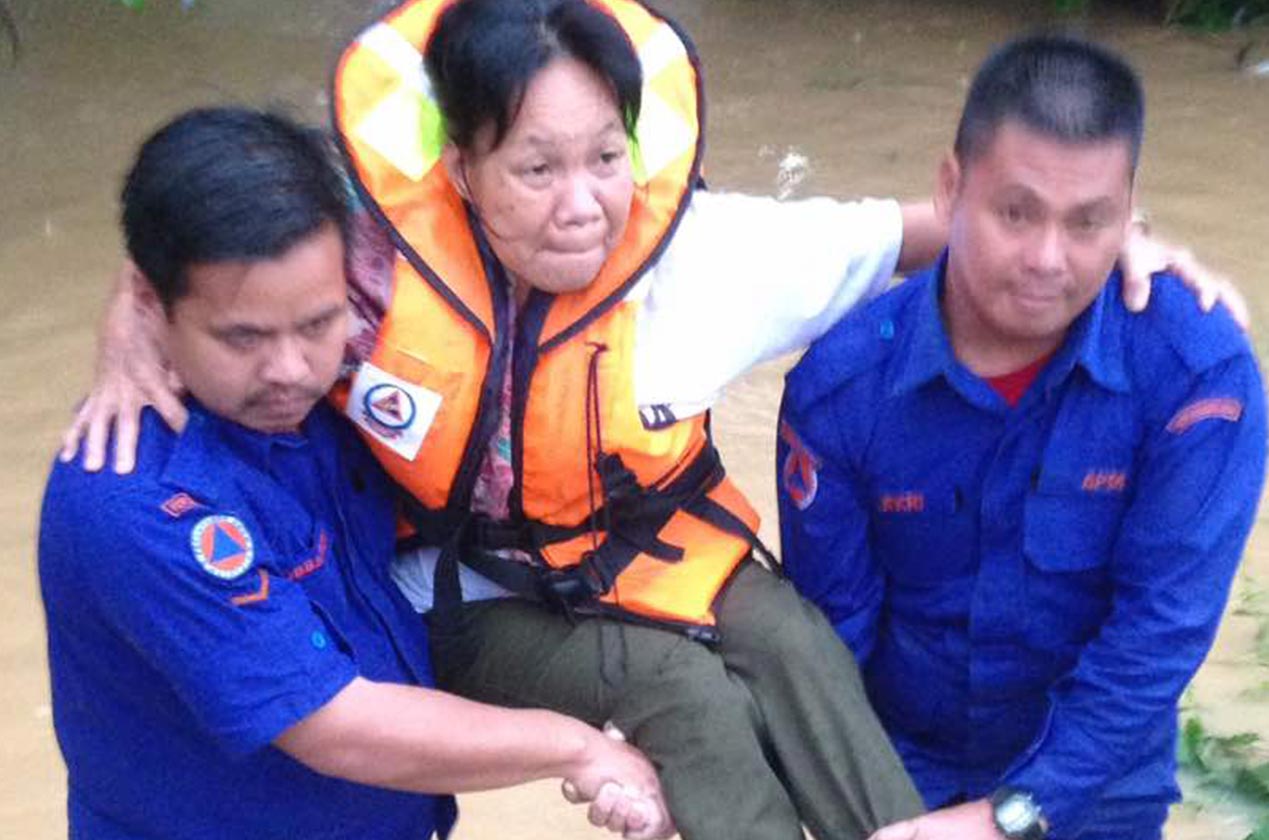 Seorang penduduk dipapah anggota APM untuk dipindahkan ke PPS selepas rumah mereka dinaiki air.
