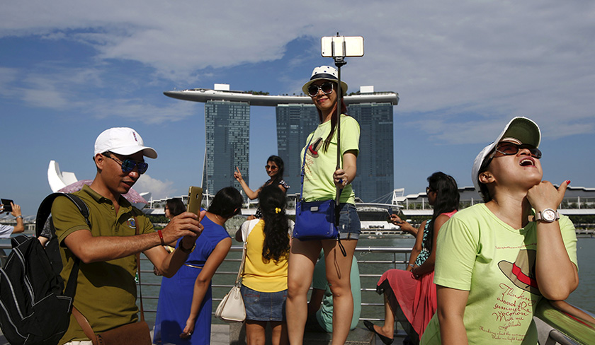 Para pelancong bergambar dengan latar belakang Marina Bay Sands di Singapura. - Gambar hiasan