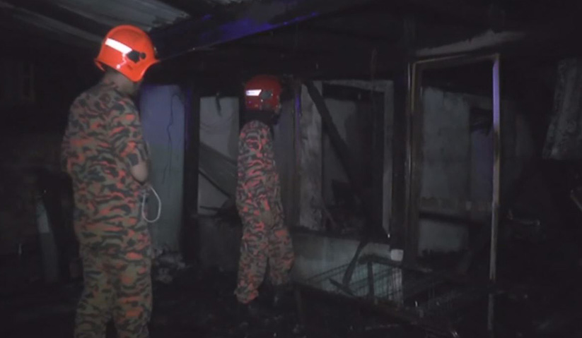 Anggota bomba memeriksa keadaan rumah yang terbakar di Kampung Kuala Bekah di Kuala Terengganu malam tadi. - Astro AWANI