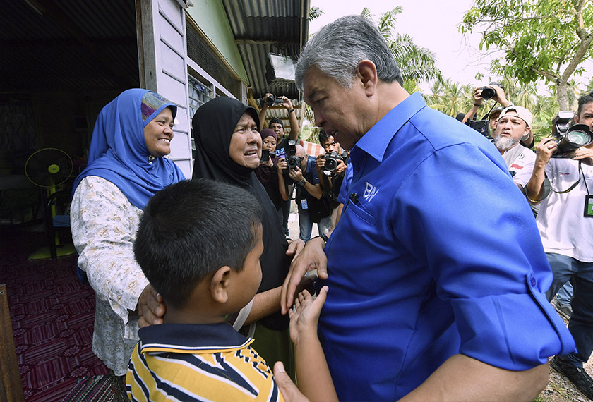 Ahmad Zahid sempat bertanya khabar pada Mahson Jamaluddin, 65, (tiga, kiri) dan keluarganya. - Foto Bernama