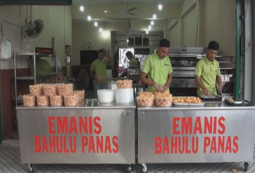 Para pekerja sibuk mengisi kuih bahulu panas ke dalam bekas.