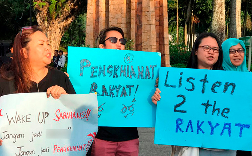 Kelihatan para penduduk Sabah berhimpun di luar pekarangan Istana Negeri membantah tindakan calon yang melompat parti.
