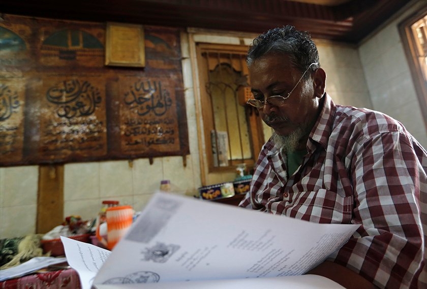 Tin Shwe meneliti surat mahkamah menegnai hukuman anaknya di kediamannya di pekan Thaketa. - Reuters