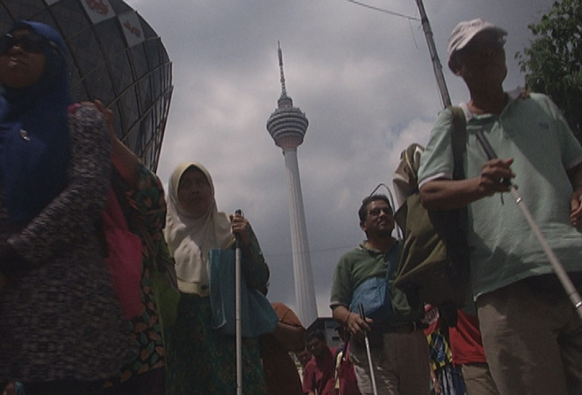 Komuniti OKU penglihatan di Kuala Lumpur beratur bagi mendapatkan pek makanan. - Astro AWANI