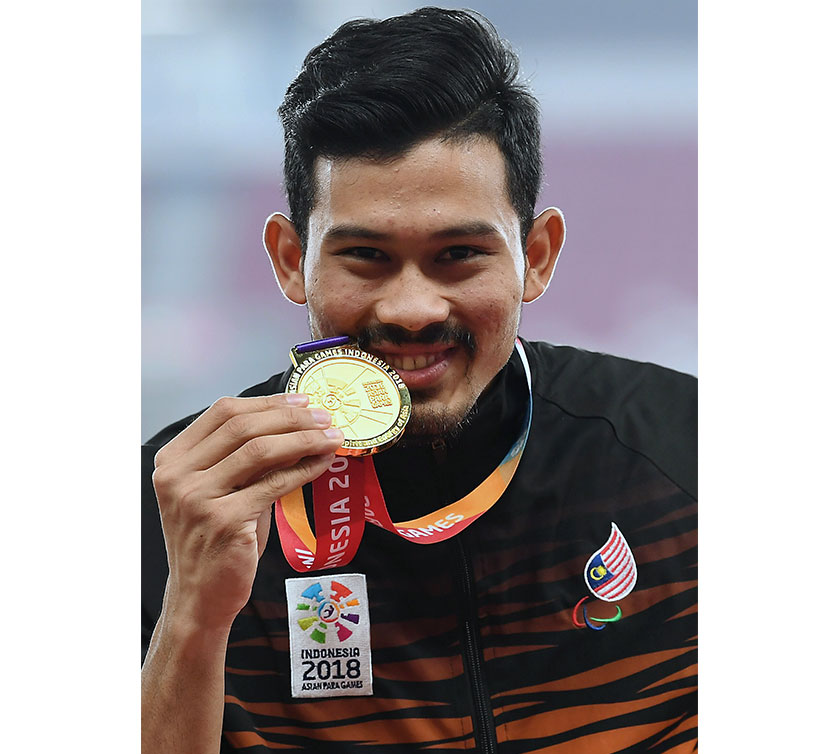Atlet negara Abdul Latif Romly menunjukkan pingat emas yang dimenangi dalam acara akhir lompat jauh kategori lelaki T20 sempena Temasya Sukan Para Asia 2018 di Stadium Gelora Bung Karno. - Foto Bernama