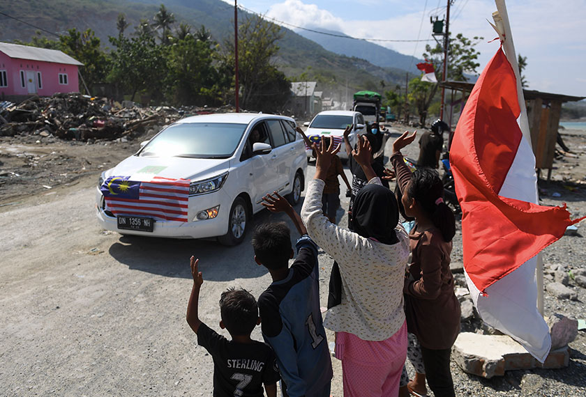 Sebahagian kanak-kanak melambaikan tangan mengucapkan terima kasih kepada konvoi misi kemanusian bencana yang diketuai oleh Majlis Perundingan Pertubuhan Islam Malaysia (MAPIM) di Jalan Malonda Kota Palu hari ini. - Bernama