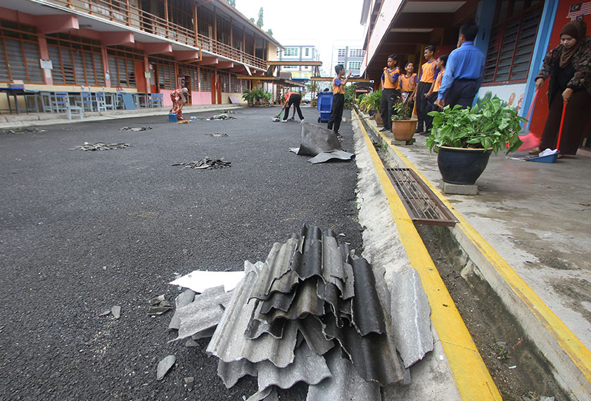 Warga Sekolah Kebangsaan Sri Perlis membersihkan kawasan sekolah setelah dipenuhi dengan serpihan atap genting akibat dilanda ribut ketika tinjauan ke sekolah berkenaan hari ini. - BERNAMA