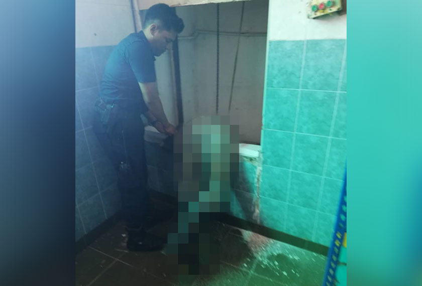 Seorang pegawai polis cuba mengalihkan mayat mangsa. - Foto PDRM/JBPM