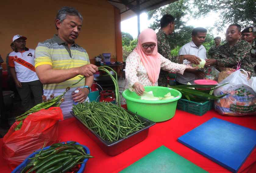 Al-Sultan Abdullah yang pada ketika itu berkenan menyandang Pemangku Raja Pahang Tengku Mahkota Pahang bersama Tunku Azizah yang pada ketika itu berkenan menyandang Tengku Puan Pahang berkenan bergotong-royong menyediakan bahan masakan sebelum memasak sendiri makanan yang akan dihidangkan kepada mangsa banjir di Pusat Pemindahan Banjir Dewan Seri Damai, Kuantan, 27 Januari 2017. -- fotoBERNAMA