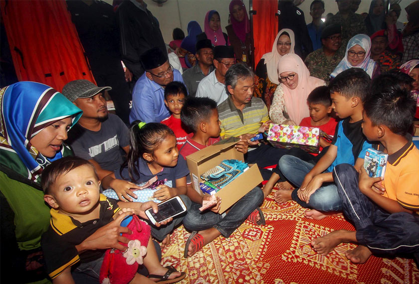 Al-Sultan Abdullah yang pada ketika itu berkenan menyandang Pemangku Raja Pahang Tengku Mahkota Pahang bersama Tunku Azizah yang pada ketika itu berkenan menyandang Tengku Puan Pahang berkenan beramah mesra dengan kanak-kanak semasa menziarahi mangsa banjir yang ditempatkan di Pusat Pemindahan Banjir Dewan Seri Damai Kuantan pada 27 Januari 2017. --fotoBERNAMA