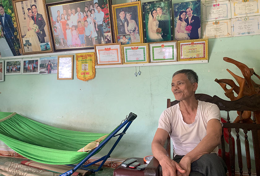 Nguyen Van Tuyen duduk di hadapan deretan gambar di dinding yang dengan bangganya memaparkan kebahagiaan keluarganya dan kejayaan anak-anaknya. - Pasukan Ceritalah